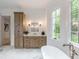 Bathroom featuring a bathtub, luxurious marble floors, and elegant cabinetry in a well lit space at 464 Pine Tree Ne Dr, Atlanta, GA 30305
