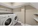 Functional laundry area featuring a washer, dryer and white shelves for added storage at 97 Peachtree Hills Ne Ave, Atlanta, GA 30305