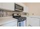 A closer look at the white cabinets, stainless steel microwave, gas range, and metallic backsplash in the kitchen at 3746 Berkeley Xing, Duluth, GA 30096