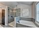 Modern bathroom features a soaking tub, a separate glass-enclosed shower, and shuttered windows at 7725 Pierpoint Ln, Alpharetta, GA 30005
