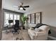 Comfortable office space features neutral walls, a ceiling fan, a desk with monitors, and a cozy chair with throw at 7725 Pierpoint Ln, Alpharetta, GA 30005