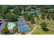 Scenic aerial view of a neighborhood with a community pool, tennis courts, and tranquil lake, surrounded by mature trees at 9889 Between The Grns, Villa Rica, GA 30180