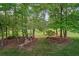 Expansive backyard featuring mature trees, lush landscaping, and a charming pergola with seating and a fire pit at 9889 Between The Grns, Villa Rica, GA 30180