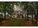 Scenic backyard view with a two-story deck, seating area, and a charming swing set amidst mature trees at 9889 Between The Grns, Villa Rica, GA 30180