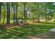 Picturesque backyard with mature trees, landscaping, and a welcoming pergola featuring seating and a fire pit at 9889 Between The Grns, Villa Rica, GA 30180