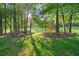 Lush backyard with mature trees, landscaping, and a cozy pergola featuring comfortable seating around a fire pit at 9889 Between The Grns, Villa Rica, GA 30180