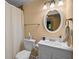 Cozy bathroom with a white toilet, vanity, framed mirror, and shower with peach colored walls at 9889 Between The Grns, Villa Rica, GA 30180