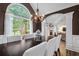 Dining room features a long dark wood table with white chairs, chandelier, and archway leading to the living area at 9889 Between The Grns, Villa Rica, GA 30180