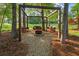 Cozy pergola nestled among mature trees, featuring comfortable seating around a fire pit, perfect for outdoor gatherings at 9889 Between The Grns, Villa Rica, GA 30180