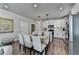 Dining area with a table for six adjacent to a modern kitchen with white cabinets at 5299 Noble Village Way, Lilburn, GA 30047