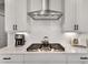 Updated kitchen featuring stainless steel range hood, gas range, white cabinets, and subway tile backsplash at 208 Idylwilde Way, Canton, GA 30115