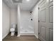 New basement bathroom with gray wood-look flooring and a white shower stall with black hardware and a toilet at 2701 Gentry Dr, Douglasville, GA 30135