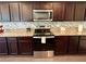 Close up of a kitchen with granite countertops, stainless steel appliances, and dark brown cabinetry at 3785 Newbury Place Dr, Loganville, GA 30052