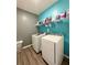 Efficient laundry room with side-by-side washer and dryer, shelving and wood-look flooring at 3785 Newbury Place Dr, Loganville, GA 30052