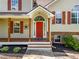 Inviting covered front porch with wood columns and a bright red front door at 405 Maple Rdg, White, GA 30184