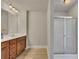 Bathroom featuring wood cabinets, a double vanity, light countertop, and glass-enclosed shower at 506 Tallapoosa Trl, Woodstock, GA 30188