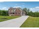 Stately brick home featuring a lush front lawn and a long driveway leading to a garage at 6375 Haystack Ct, Cumming, GA 30040