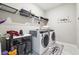 Well-lit laundry room featuring white marble floors, modern washer and dryer, and shelving at 6375 Haystack Ct, Cumming, GA 30040
