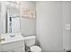 A clean half bathroom features a crisp white vanity, toilet, and neutral wall decor for a minimalist aesthetic at 1314 Durham Ter, Mcdonough, GA 30252