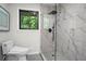 Shower with marble-style tile and glass enclosure; window overlooking green space at 1749 Ridge Valley Nw Ct, Atlanta, GA 30327