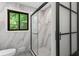 Stylish bathroom showcasing glass enclosed walk-in shower, marble style tile, and a window at 1749 Ridge Valley Nw Ct, Atlanta, GA 30327