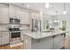 Bright kitchen features stainless appliances, island with granite countertops, and ample cabinet space at 302 Braswell Ct, Woodstock, GA 30188