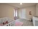 Serene bedroom with a white crib, dresser, and pink accents, offering a calm and nurturing environment at 157 Oliver Dr, Locust Grove, GA 30248