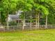 Charming two-story home with red shutters, a covered porch, and a rustic wooden fence surrounding the lush front yard at 173 Price Rd, Brooks, GA 30205