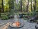 Inviting outdoor patio with a stone fire pit, surrounded by lush greenery and mature trees at 173 Price Rd, Brooks, GA 30205