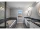 Bright bathroom featuring tiled floors, double sinks, granite countertops, and a soaking tub at 2548 Kickerillo Se Way, Atlanta, GA 30316