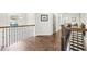 Spacious upstairs hallway featuring hardwood floors, a wrought iron railing, and modern lighting at 2652 Brickell Sq, Atlanta, GA 30341