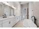 A stylish bathroom with double vanity, freestanding tub, and marble-style tiling for a luxurious retreat at 91 Batten Board Way, Woodstock, GA 30189