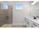 Modern bathroom featuring tiled shower with glass door, white vanity with black hardware, and bright window at 91 Batten Board Way, Woodstock, GA 30189