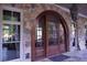 Arched wood front door with stone and stucco surround at 91 Batten Board Way, Woodstock, GA 30189