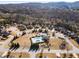 Community aerial view showcases pool, clubhouse, homes, and tree-lined streets surrounded by mountain views at 6280 Stillwood Ln, Cumming, GA 30041