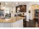 This kitchen boasts granite countertops, stainless steel appliances, and dark wood cabinets with views into the dining area at 6280 Stillwood Ln, Cumming, GA 30041