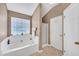 Bright bathroom featuring a large soaking tub with white tile surround and a window for natural light at 1332 Kent Mnr, Stockbridge, GA 30281