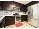 Galley kitchen features dark cabinets, stainless steel appliances, and tile backsplash at 1239 Sharonton Dr, Stone Mountain, GA 30083