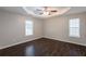 Spacious bedroom featuring hardwood floors, a tray ceiling, and natural light from two windows at 4045 Meadow Glen Way, Fairburn, GA 30213