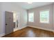 Bedroom features hardwood floors, two windows with blinds, and a view into an ensuite bathroom at 1142 Wiley Bridge Rd, Woodstock, GA 30188
