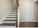 Staircase featuring wood steps, white risers, and a white railing, next to a white door at 2444 Coosa Vly, Atlanta, GA 30339