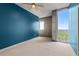 Bedroom featuring carpet flooring, blue accent wall, ceiling fan, and large windows with city views at 855 Peachtree Ne St # 2713, Atlanta, GA 30308