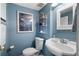 Cozy powder room with blue walls, pedestal sink, and decorative artwork at 5 Newport Nw Pl, Atlanta, GA 30318