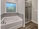 Bathroom with gray tile surround, tub, and glass-enclosed shower provides a spa-like experience at 5291 Tuscany Dr, Douglasville, GA 30135