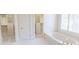 Bright bathroom featuring a large walk-in closet, soaking tub, and natural light from the window at 5685 Commons Ln, Alpharetta, GA 30005