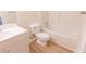 Bright bathroom featuring a toilet, tub, and vanity with laminate floors and neutral walls at 5685 Commons Ln, Alpharetta, GA 30005