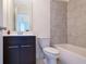 Bathroom featuring a tub, toilet, dark cabinets, white countertops and gray accent wall at 7850 Willoughby Ct, Alpharetta, GA 30005