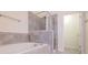 Inviting bathroom featuring a soaking tub with gray stone surround, glass shower, and tile floors at 7850 Willoughby Ct, Alpharetta, GA 30005