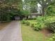 A single-story brick home featuring mature landscaping, a long driveway, and an attached one-car garage at 1517 Colony East Cir, Stone Mountain, GA 30083