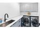 Well-lit laundry room with gray cabinets, a stainless steel sink, and modern washer/dryer at 2577 Kilgore Rd, Buford, GA 30519